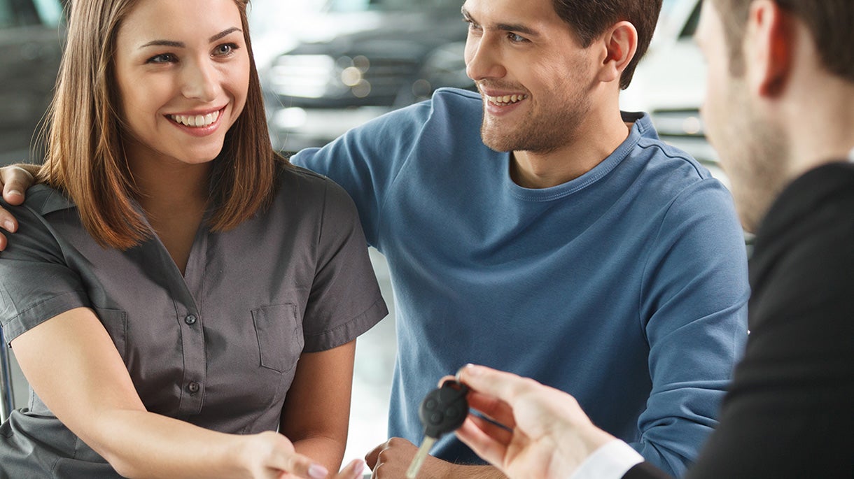 Salesman handing car keys to couple