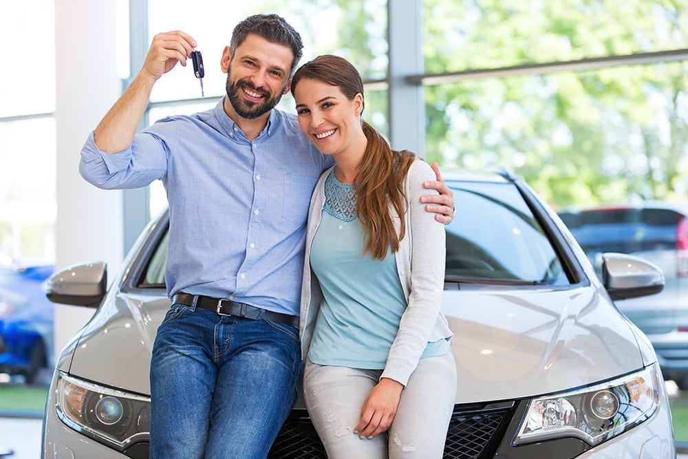 Happy couple holding keys to their vehicle