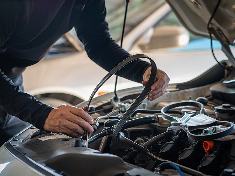 Automotive technician checking vehicle car belt